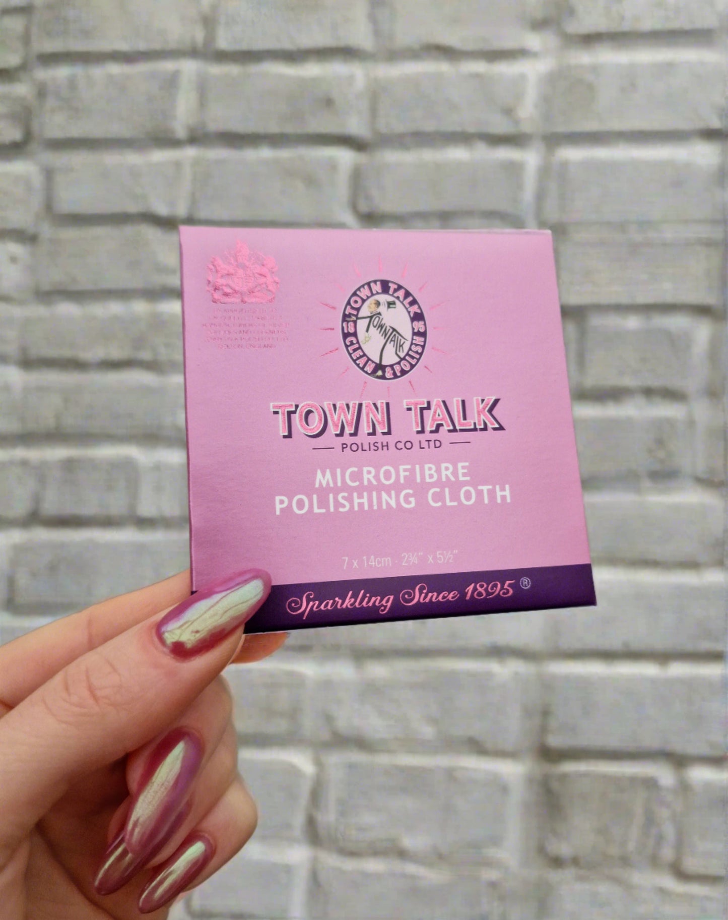  Outer packaging for the microfiber jewellery cloth. A small purple packet with Town Talk logo on the front. Brick wall as a background.