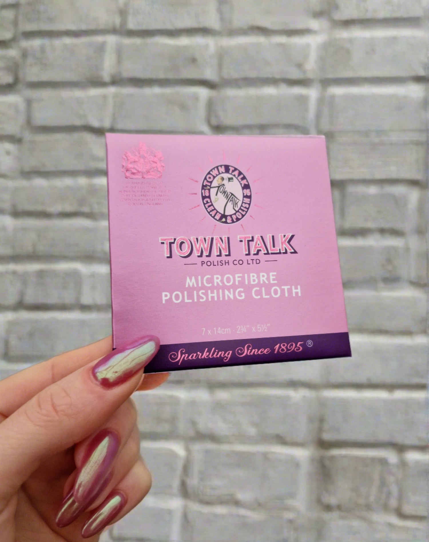  Outer packaging for the microfiber jewellery cloth. A small purple packet with Town Talk logo on the front. Brick wall as a background.
